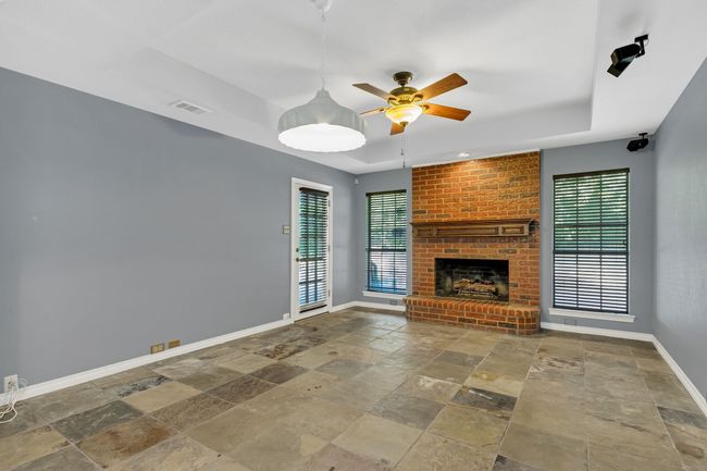 Unfurnished living room with stone tile flooring, a raised ceiling, healthy amount of natural light, and a ceiling fan | Image 11