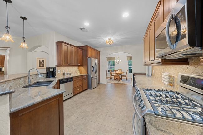 The current owners gutted and enlarged this amazing kitchen! Notice the gorgeous cabinets, the incredible storage and counter space, the lovely neutral granite counters, and stainless steel appliances including a wine fridge! | Image 5