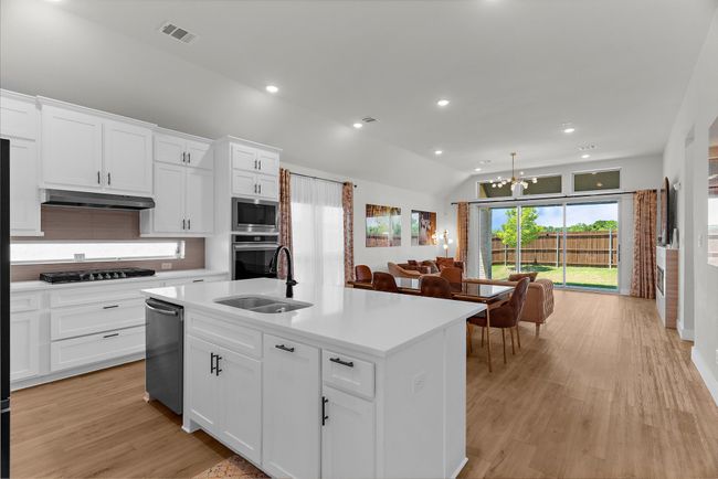 Kitchen featuring appliances with stainless steel finishes, under cabinet range hood, a chandelier, light countertops, and recessed lighting | Image 12