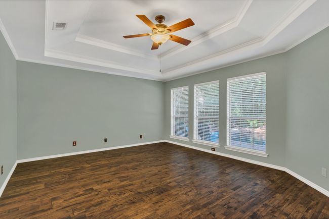 Unfurnished room featuring a tray ceiling, ceiling fan, dark wood-type flooring, and ornamental molding | Image 17