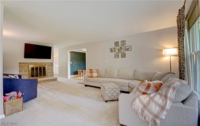 Carpeted living room featuring a stone fireplace and baseboards | Image 12