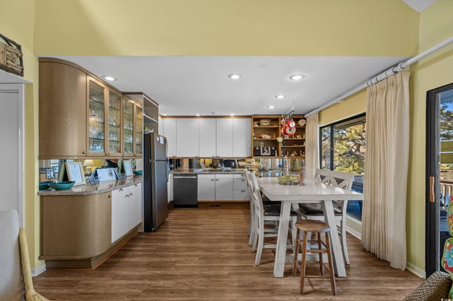 Kitchen featuring freestanding refrigerator, open shelves, dark wood-style floors, dishwashing machine, and white cabinets | Image 14
