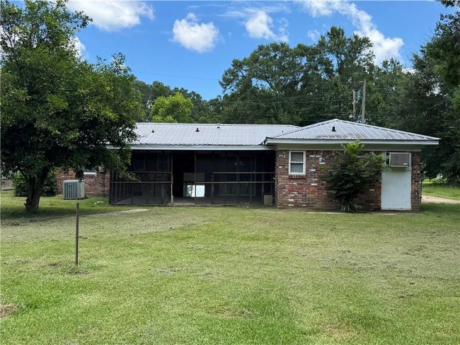 Rear view of house with a sunroom, a lawn, and a metal roof | Image 17