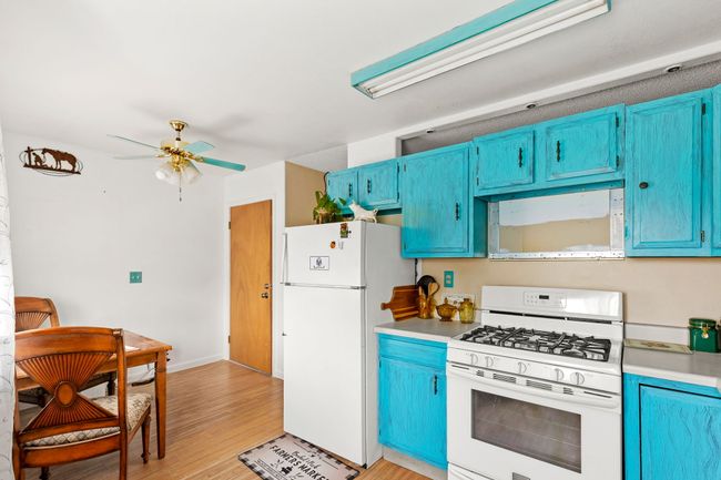 Separate apartment above garage - Kitchen with ceiling fan, blue cabinetry, and white appliances | Image 69