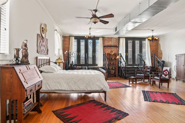 Bedroom featuring hardwood / wood-style flooring, brick wall, french doors, an inviting chandelier, and crown molding | Image 30