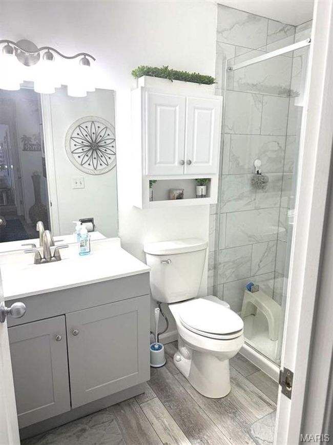 Bathroom featuring a stall shower, vanity, toilet, and wood finished floors | Image 29