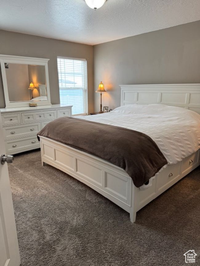 Bedroom with dark carpet and a textured ceiling | Image 13