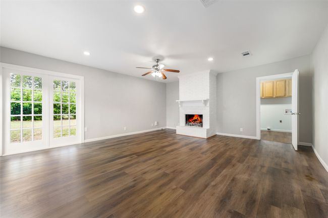 Unfurnished living room featuring a ceiling fan, a brick fireplace, recessed lighting, and dark wood-style floors | Image 34