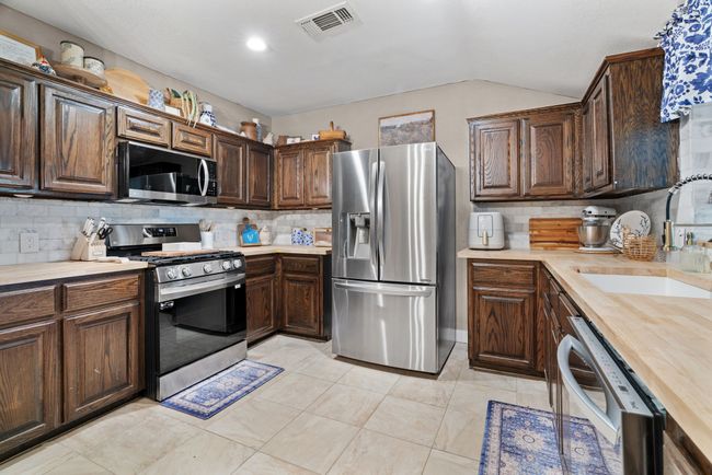 Kitchen with stainless steel appliances, vaulted ceiling, backsplash, and dark brown cabinets | Image 13