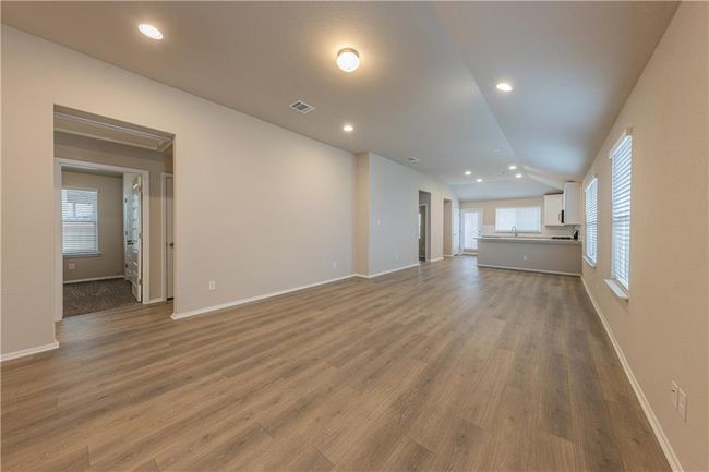 Unfurnished living room featuring wood finished floors, a sink, baseboards, recessed lighting, and vaulted ceiling | Image 6