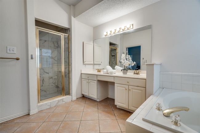 Full bathroom featuring a marble finish shower, double vanity, a garden tub, and tile patterned flooring | Image 15