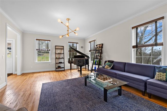 Living area with crown molding, baseboards, a notable chandelier, and wood finished floors | Image 6