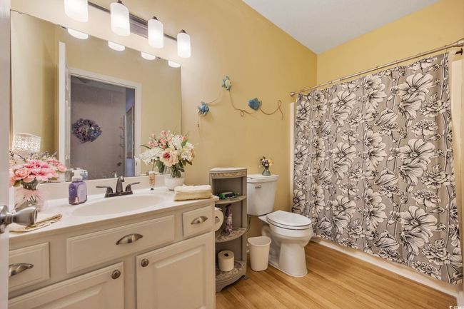 Full bath with wood finished floors, toilet, vanity, and a shower with shower curtain | Image 18