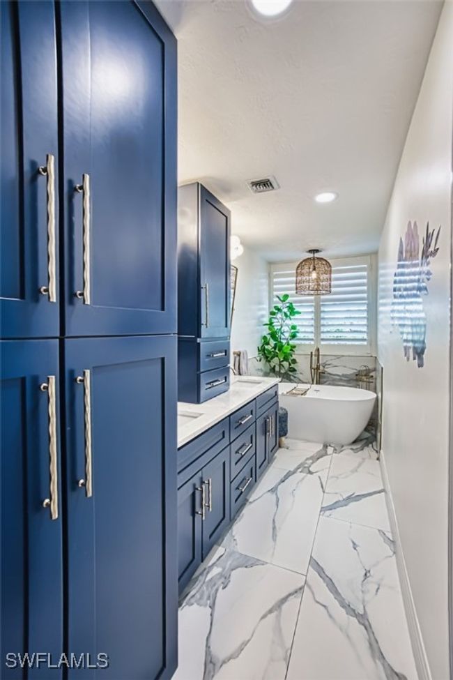 Bathroom featuring a freestanding bath, double vanity, marble finish flooring, and recessed lighting | Image 30