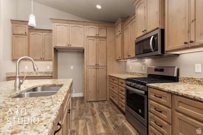 Kitchen with appliances with stainless steel finishes, dark wood finished floors, light stone counters, light brown cabinets, and pendant lighting | Image 16