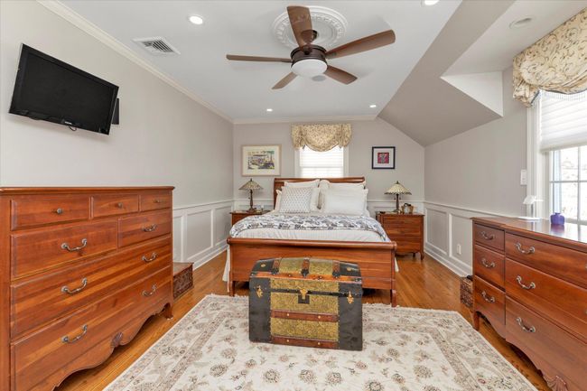 Bedroom with wainscoting, crown molding, wood finished floors, and visible vents | Image 9