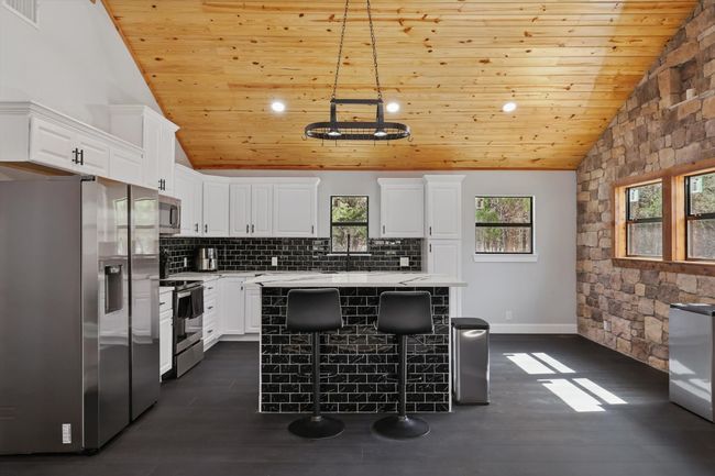 Kitchen with visible vents, wood ceiling, white cabinets, light countertops, and appliances with stainless steel finishes | Image 4
