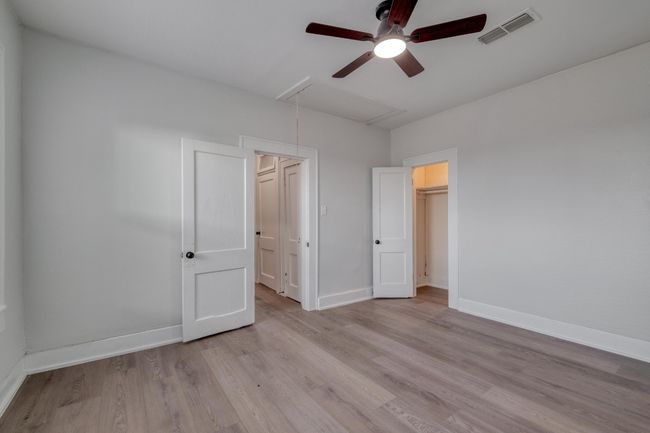 Unfurnished bedroom with attic access, wood finished floors, ceiling fan, and a walk in closet | Image 34