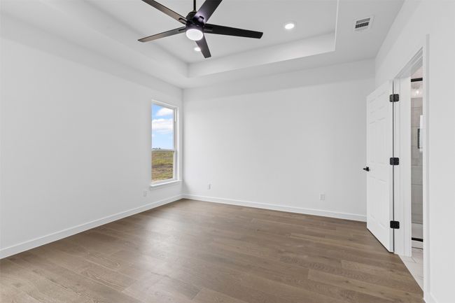 Spare room with a ceiling fan, wood finished floors, baseboards, a tray ceiling, and recessed lighting | Image 29