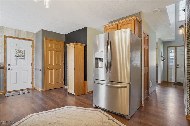 Kitchen with dark wood-style floors, a textured ceiling, stainless steel refrigerator with ice dispenser, and baseboards | Image 17