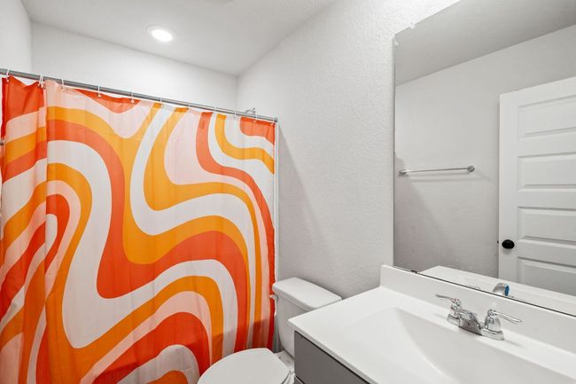 Bathroom featuring a textured wall, vanity, a shower with shower curtain, and toilet | Image 22