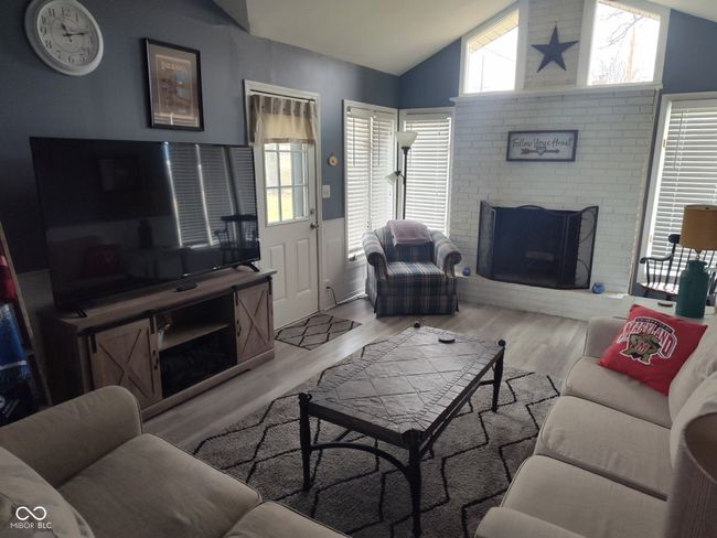 family room with a wealth of natural light, lofted ceiling, a brick fireplace, and wainscoting | Image 4
