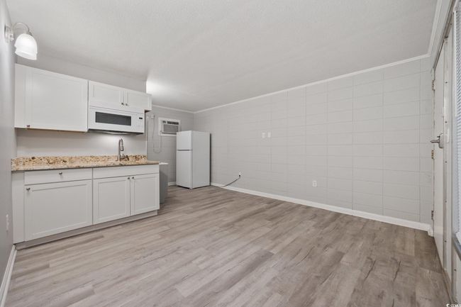 Kitchen featuring white appliances, a sink, light wood-type flooring, and white cabinets | Image 6