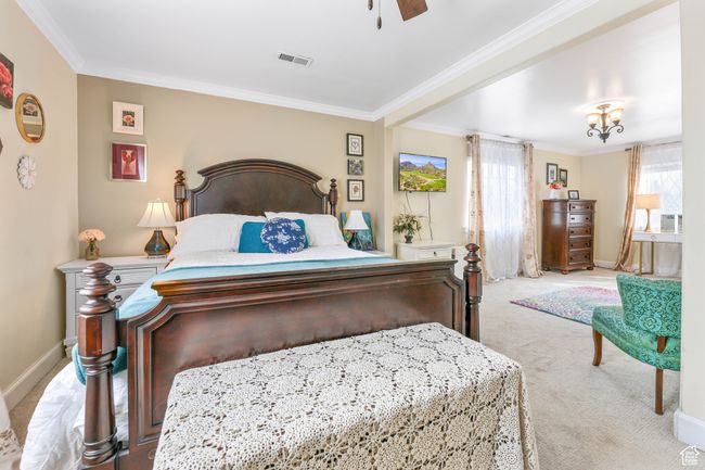 Carpeted bedroom with baseboards, a ceiling fan, visible vents, and crown molding | Image 23