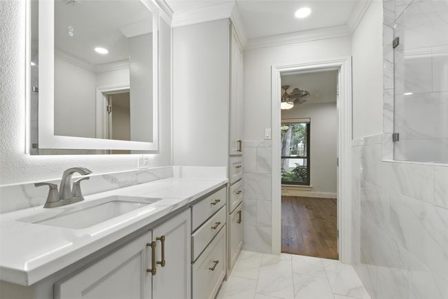Bathroom featuring crown molding, vanity, marble look tile flooring, a shower stall, and recessed lighting | Image 30