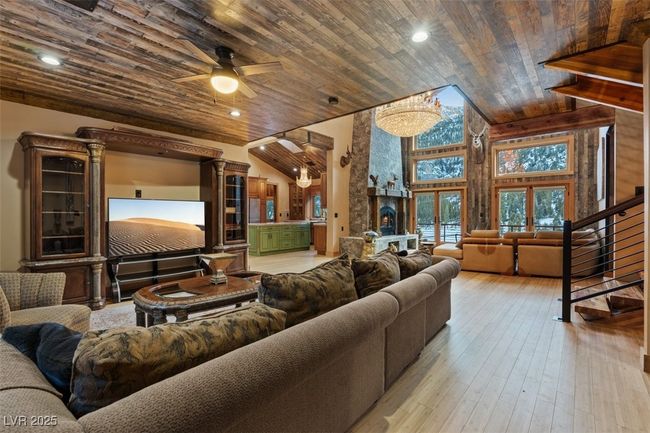 Living room featuring wood-type flooring, a ceiling fan, high vaulted ceiling, wooden ceiling, and stairs | Image 30