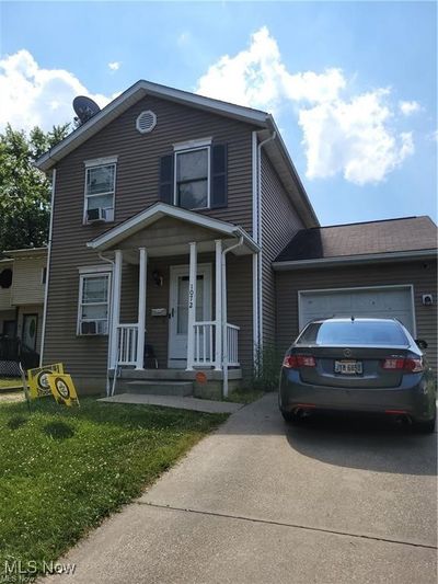 View of front of property with cooling unit, a front lawn, a porch, and a garage | Image 1