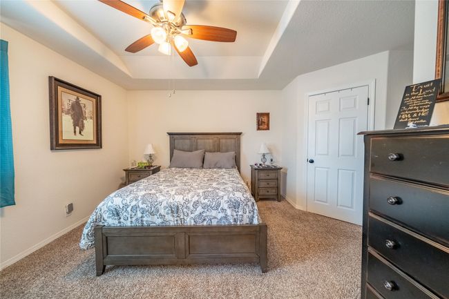 Bedroom with a raised ceiling, a ceiling fan, baseboards, and light carpet | Image 9