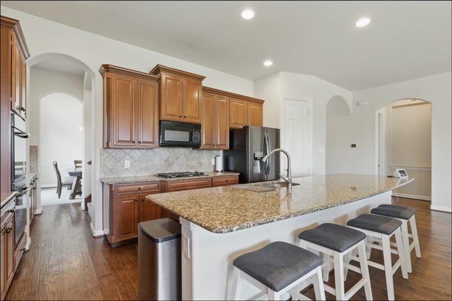 Kitchen featuring black appliances, brown cabinets, tasteful backsplash, and recessed lighting | Image 13
