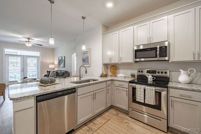 Kitchen with appliances with stainless steel finishes, light hardwood / wood-style flooring, kitchen peninsula, and sink | Image 2