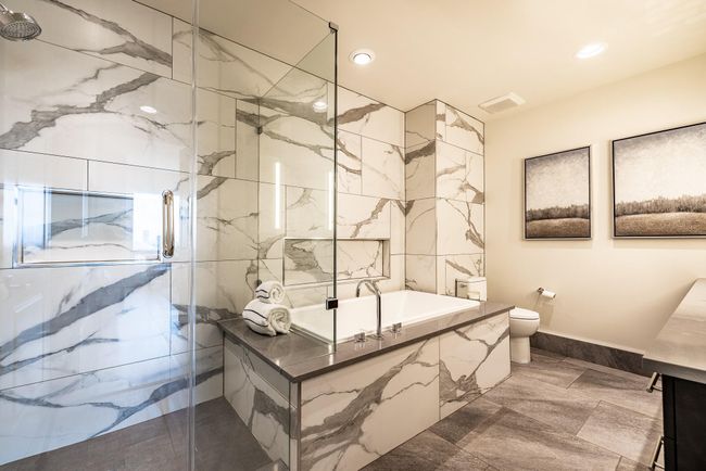 Luxurious bathroom featuring a sleek glass-enclosed shower and elegant bathtub, complemented by stylish tilework. | Image 15