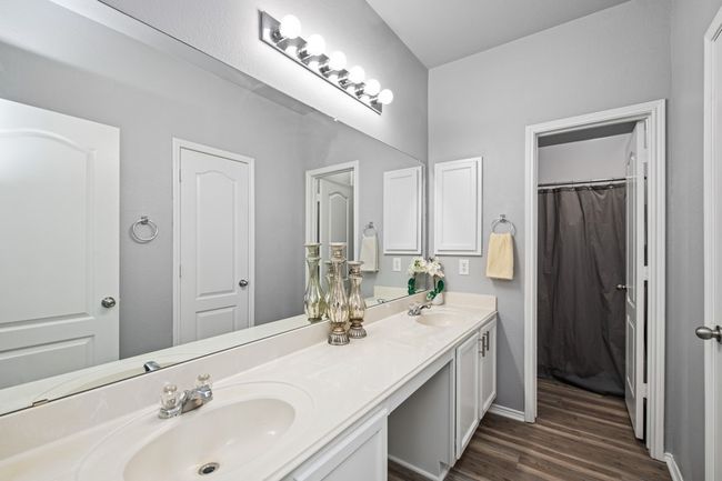 Full bathroom with double vanity, baseboards, a sink, and wood finished floors | Image 27