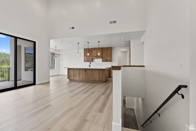 Kitchen featuring light countertops, a spacious island, brown cabinets, visible vents, and light wood-style floors | Image 31