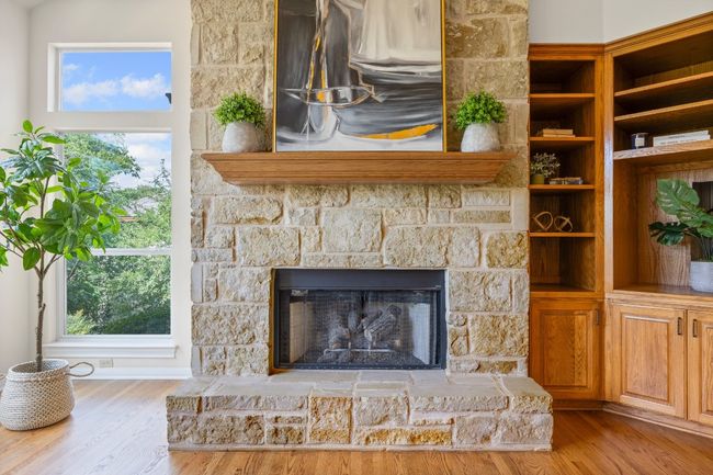 A striking Lueders stone fireplace serves as the heart of the living room, offering both gas and wood-burning options. Custom built-in cabinetry adds style and function, providing the perfect space for your TV and treasured decor. | Image 8
