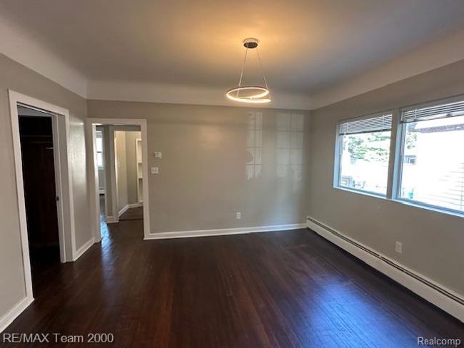 Unfurnished dining area featuring dark wood-style flooring and a baseboard heating unit | Image 10
