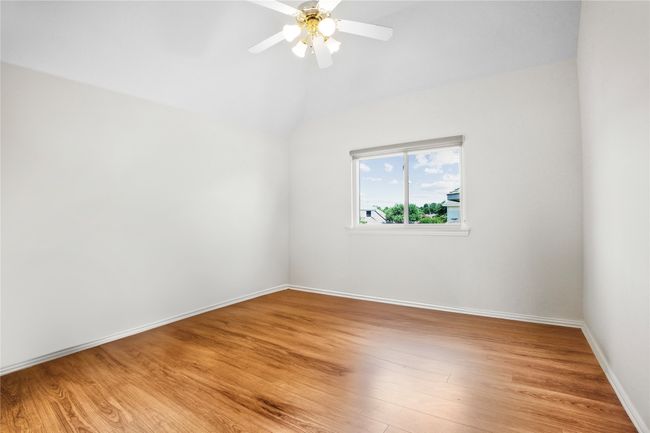 Spare room featuring light wood-style floors, lofted ceiling, and a ceiling fan | Image 29