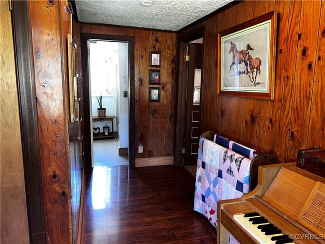 Hall featuring dark hardwood / wood-style flooring, wood walls, and a textured ceiling | Image 24