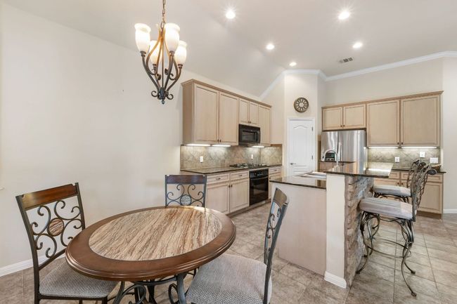 Kitchen featuring black appliances, dark countertops, light brown cabinets, tasteful backsplash, and crown molding | Image 15