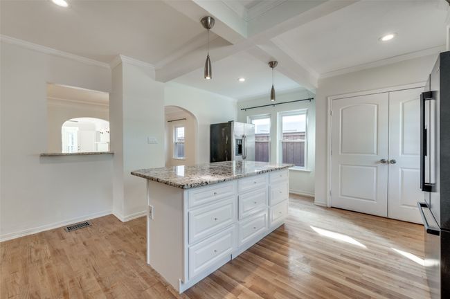 Kitchen featuring stainless steel fridge, arched walkways, beamed ceiling, white cabinets, and crown molding | Image 14