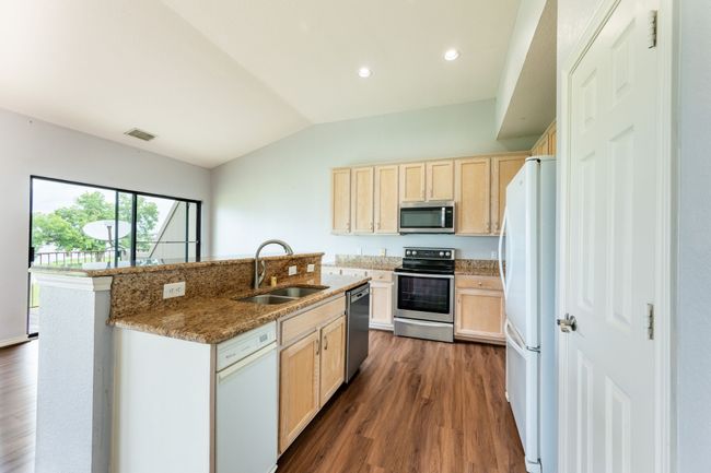 Kitchen with dark wood finished floors, lofted ceiling, light brown cabinets, appliances with stainless steel finishes, and recessed lighting | Image 11