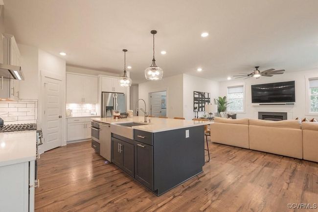 Kitchen with white cabinets, decorative backsplash, a ceiling fan, wood finished floors, and recessed lighting | Image 27