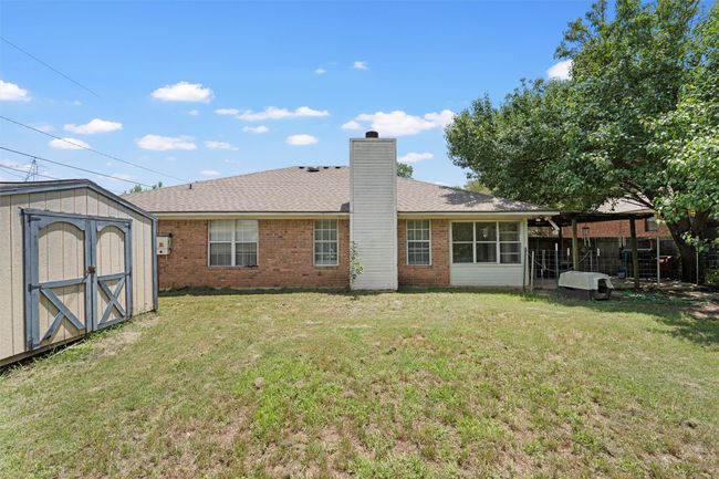 Rear view of house with brick siding, a chimney, and a shingled roof | Image 21