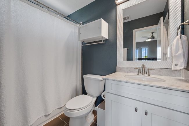 Bathroom featuring vanity, a shower with curtain, a ceiling fan, toilet, and visible vents | Image 18