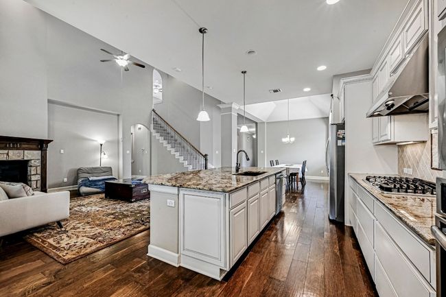 Kitchen featuring appliances with stainless steel finishes, ceiling fan, open floor plan, under cabinet range hood, and dark wood-style floors | Image 12