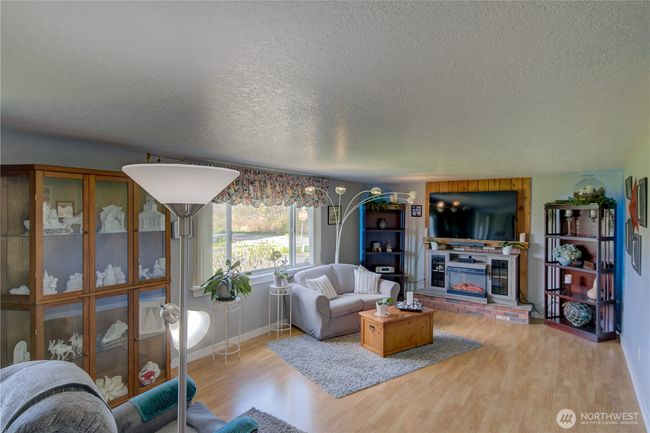Large well lit living room with a real fireplace behind the electric fireplace. | Image 11