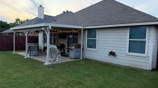 Back of house at dusk with a patio area, roof with shingles, and a chimney | Image 25